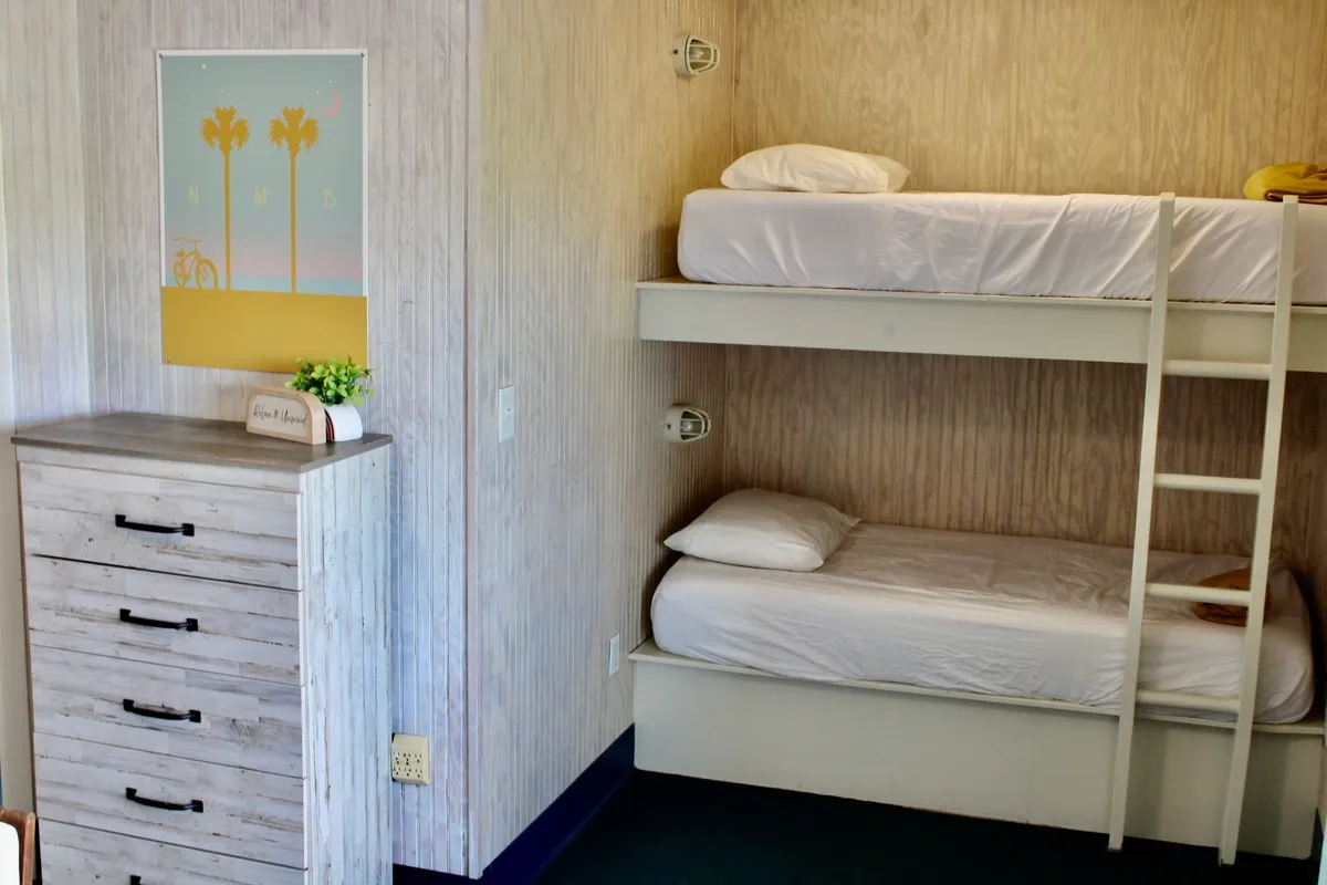 A relaxed nook featuring bunk beds, a dresser, and playful wall art. The setup is ideal for families or groups, providing flexible sleeping arrangements and space for late-night talks or reading sessions.
