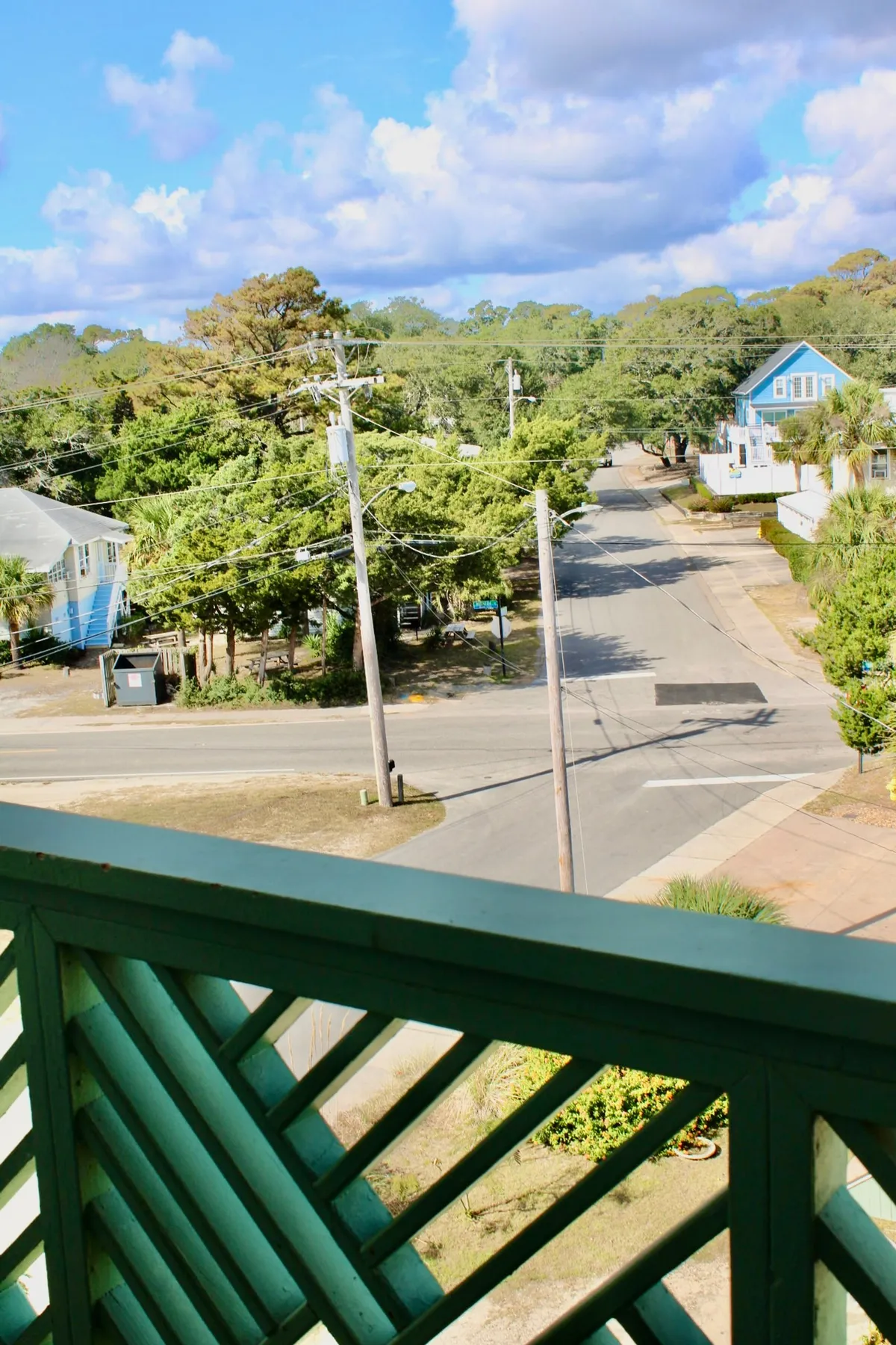 This image captures a peaceful balcony scene, complete with a view over the street, surrounding houses, and lush landscape greenery. The scene suggests an inviting spot for morning coffee while overlooking the outside world, and hints at the ease of stepping out for a stroll along nearby walkable areas.